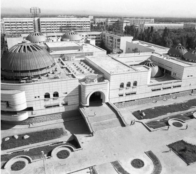 A large, multi-dome building complex with a central archway and surrounding landscaped areas. 2