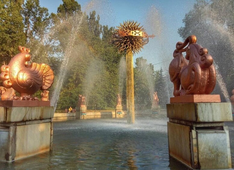 A fountain with bronze sculptures of a rooster and a ram, surrounded by water jets. 5