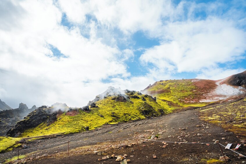 Een bergachtig landschap met groene begroeiing, rotsachtig terrein en een heldere lucht. 3
