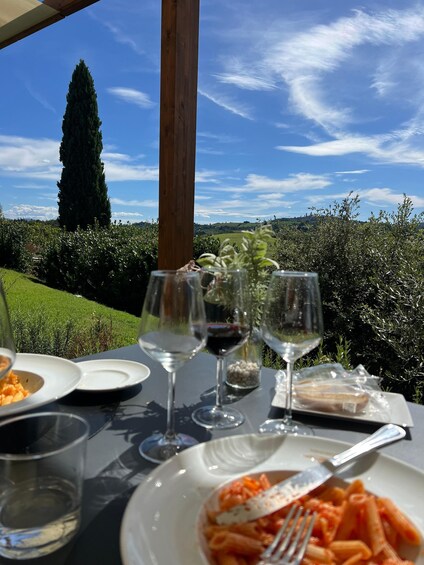 A table set outdoors with wine glasses, plates of food, and a view of a green landscape. 3