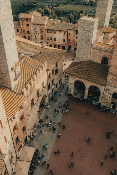 An aerial view of a historic square with buildings, a central open area, and people walking. 1