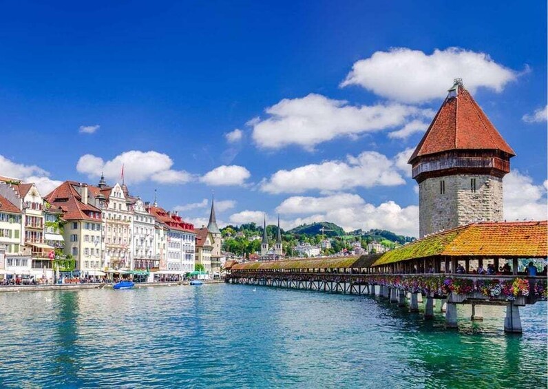 A river with a tower, colorful buildings, and a covered walkway. 1