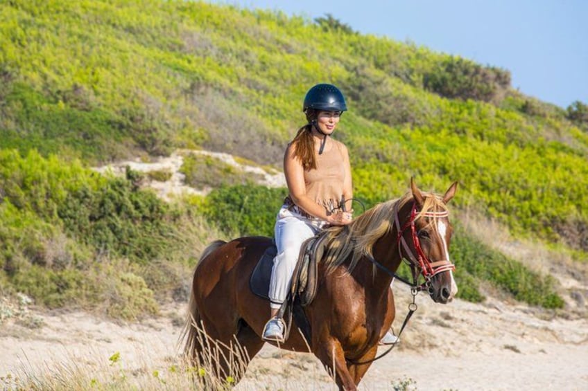 Une personne à cheval sur un chemin de terre, avec une végétation verdoyante en arrière-plan. 5