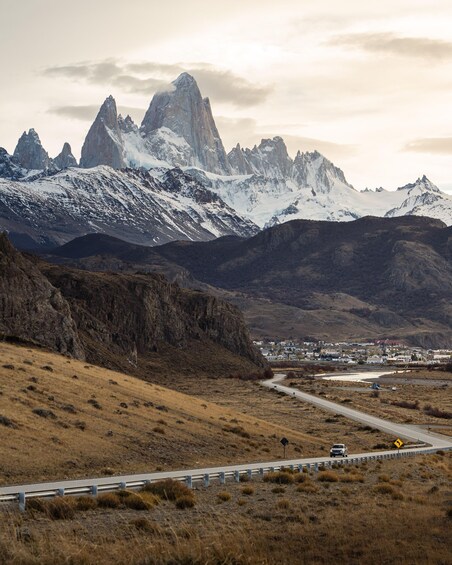 A mountain range with snow-capped peaks, a winding road, and a small settlement in the valley. 5
