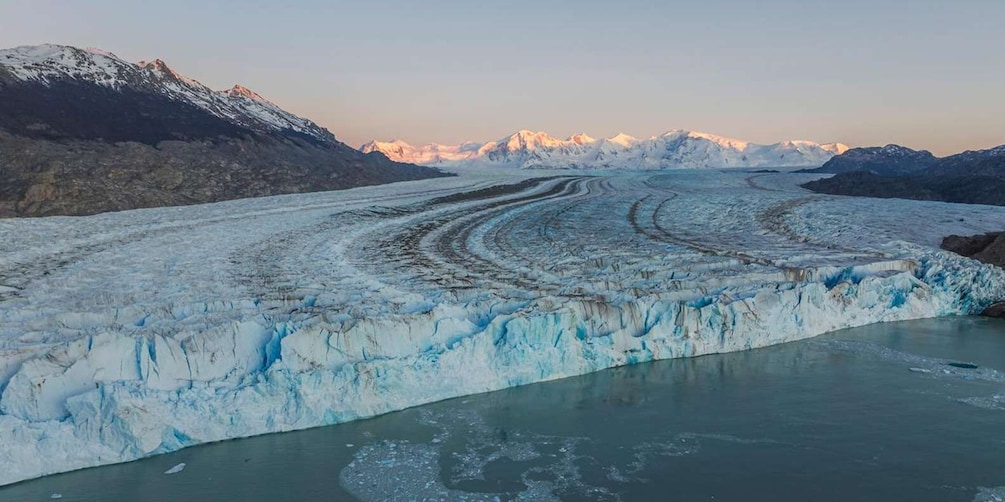A glacier with a crevasse and a mountain range in the background. 1