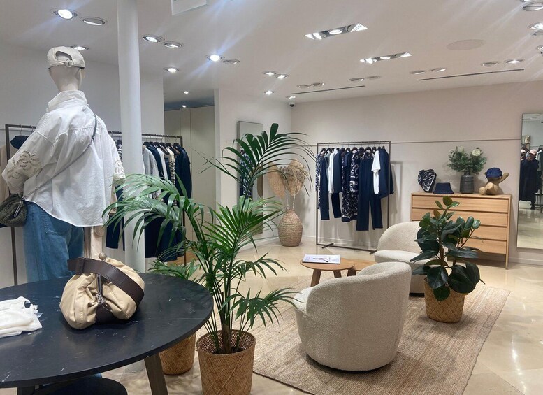 A clothing store interior with mannequins, racks of clothes, and potted plants. 4