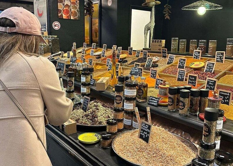 A person browsing through a variety of spices and grains at a market stall. 3