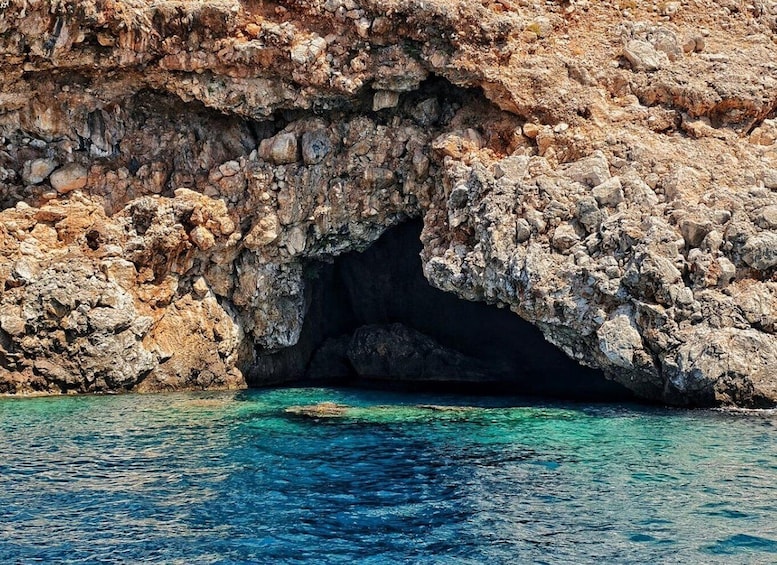 A rocky coastal cave entrance with clear blue water. 5