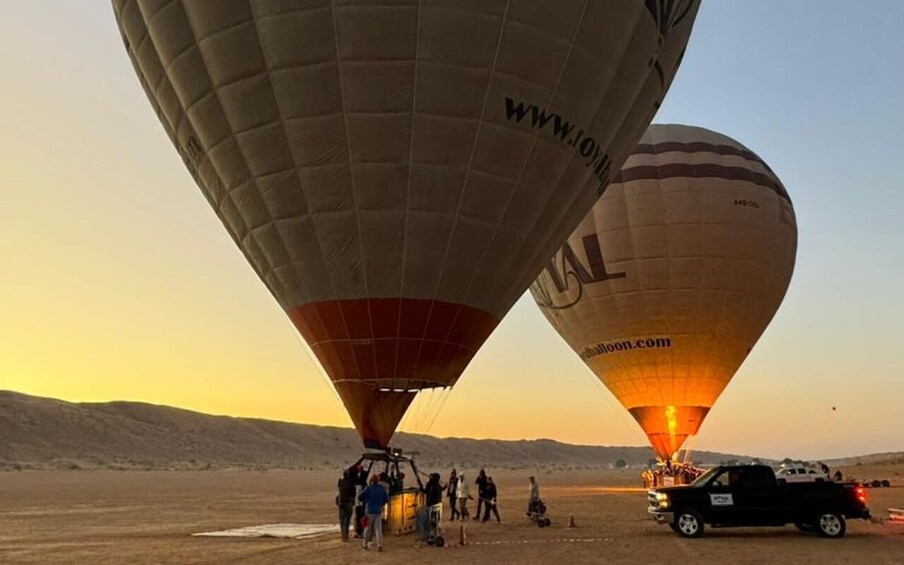 Two hot air balloons with people around them in a desert landscape. 4