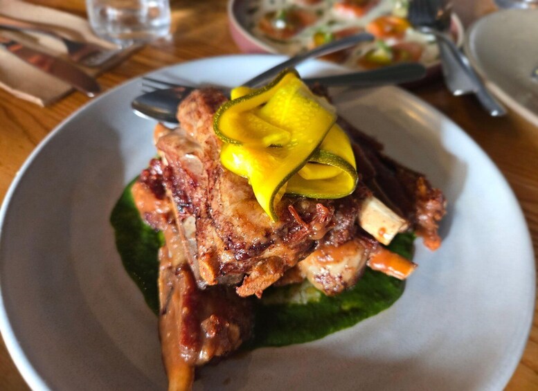 A plate of food with grilled meat, a slice of yellow fruit, and a green leaf garnish. 5
