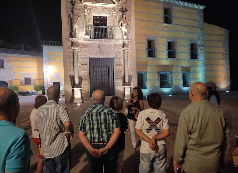 A group of people standing in front of a building with a large entrance and statues. 5