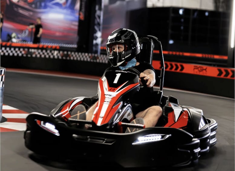 A go-kart racer in a black and red go-kart on a track. 1