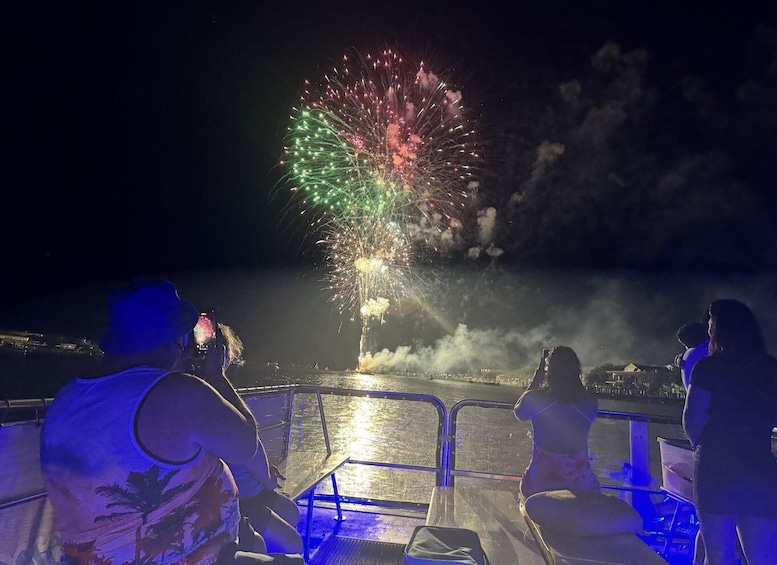 A boat with people watching fireworks over a body of water. 2