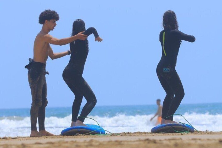 Zwei Personen surfen am Strand, im Hintergrund der Ozean. 2