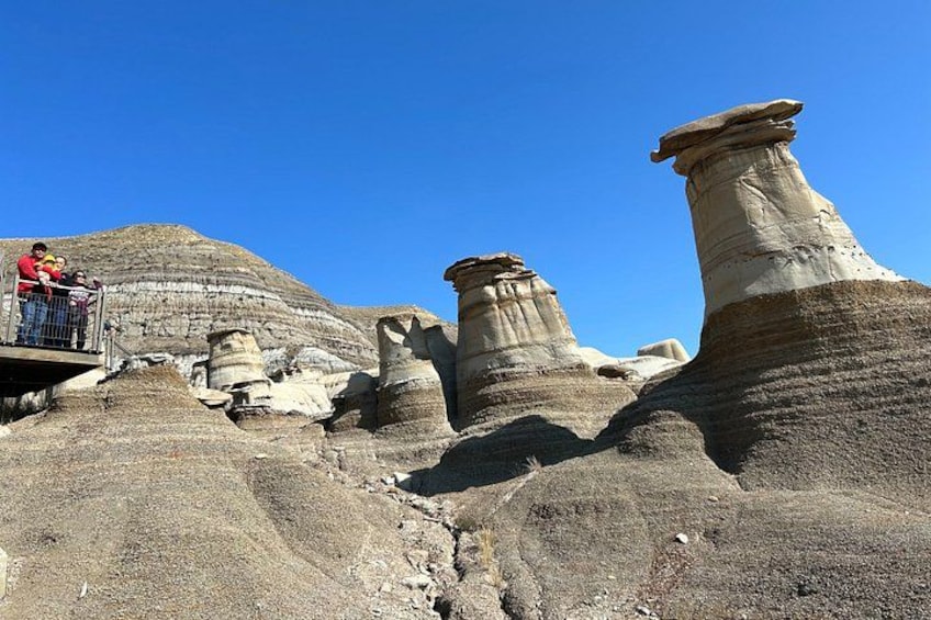 A rocky landscape with prominent hoodoos and a viewing platform with people. 5