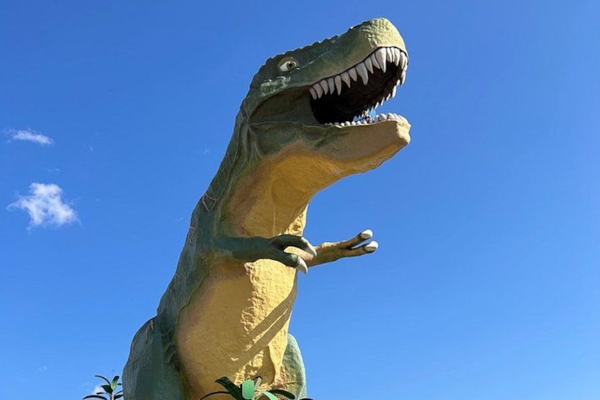 A large dinosaur statue with its mouth open, set against a clear blue sky. 4