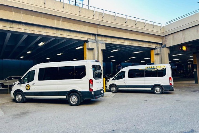 Two white vans parked in a covered parking area with a concrete structure overhead. 3