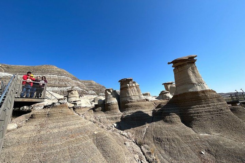 A landscape with distinctive rock formations, a viewing platform, and a clear blue sky. 4