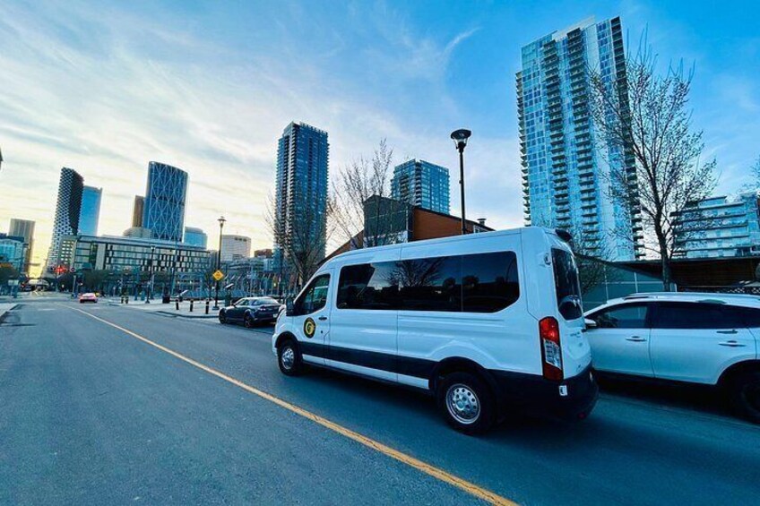 A white van parked on a city street with tall buildings in the background. 2