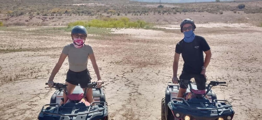 Deux personnes à bord de quads évoluent sur un terrain aride et craquelé, où la végétation est rare. 5