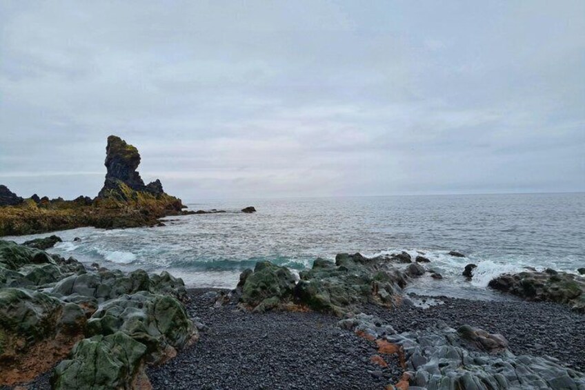 A rocky coastline with a prominent rock formation and calm sea. 3
