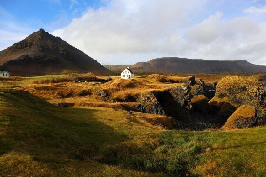 A white house in a rural landscape with rolling hills and a mountain in the background. 4