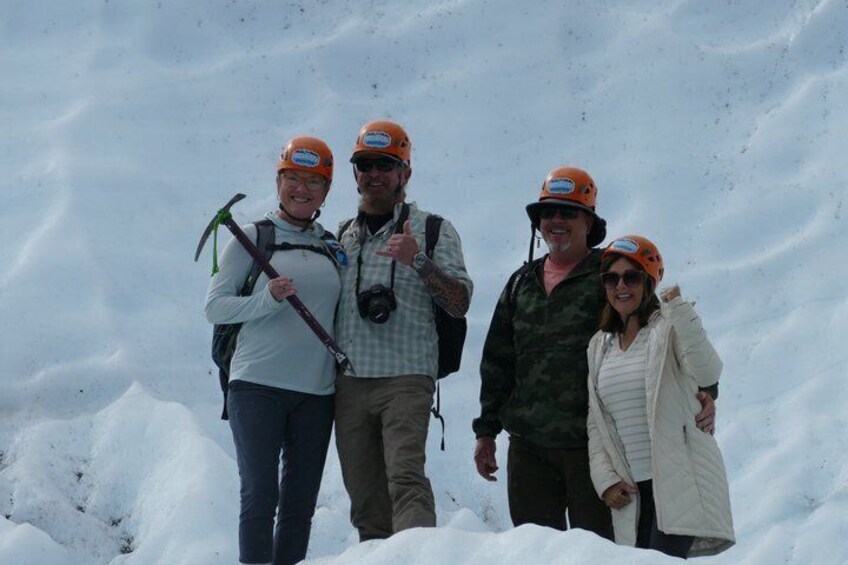 Quattro persone con abbigliamento da neve, caschi e bastoncini da trekking, in piedi su un pendio innevato. 5