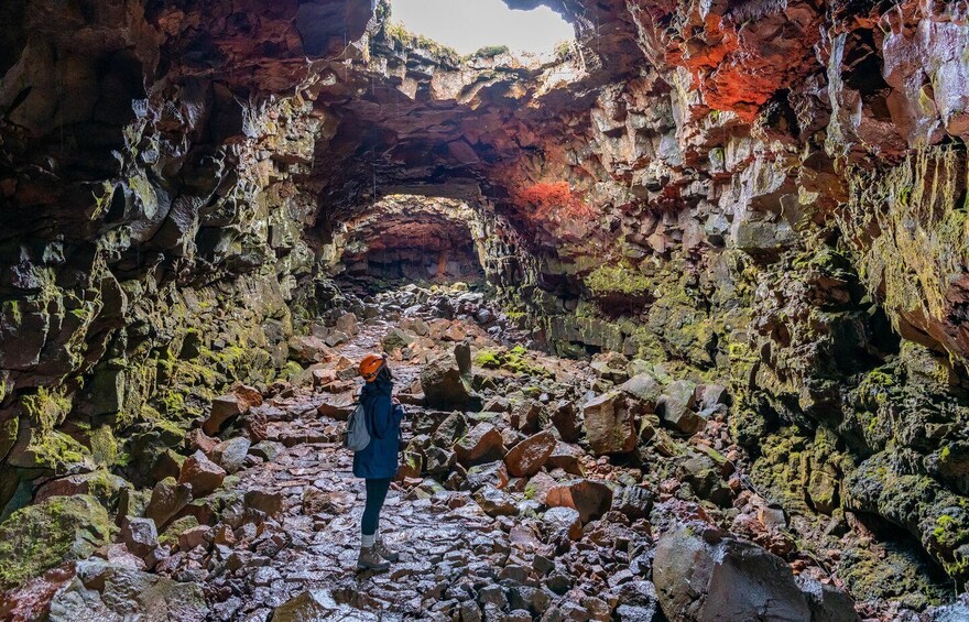 A person standing in a rocky cave with a large archway. 4