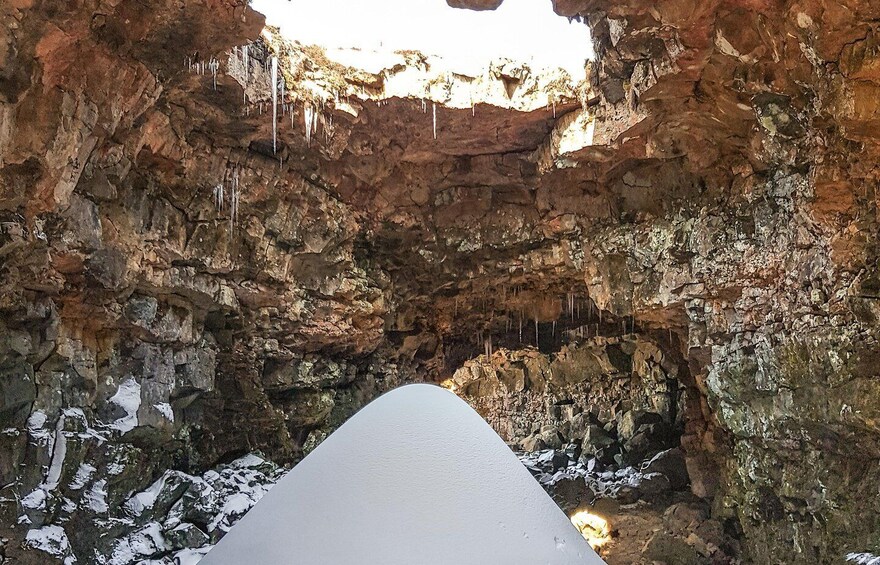 A snow-covered cave entrance with stalactites hanging from the ceiling. 3