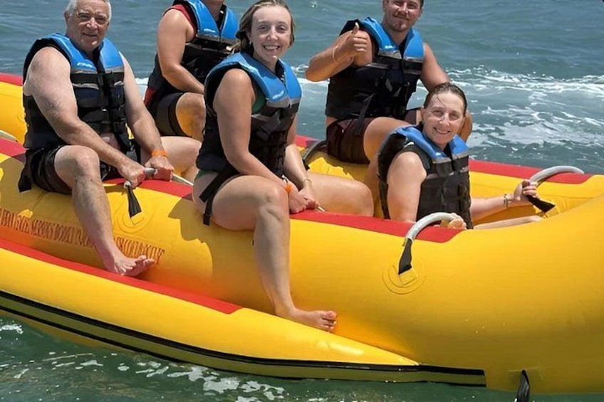 A group of people on a yellow inflatable raft with life jackets, floating on water. 2