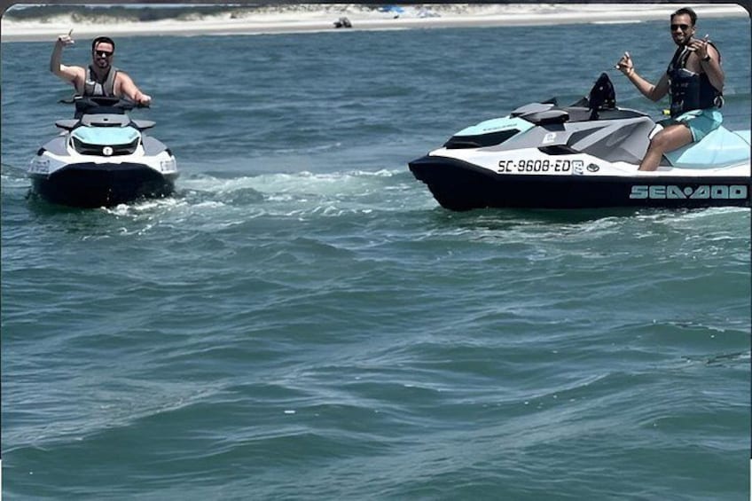 Two jet skis on a body of water with a beach in the background. 4