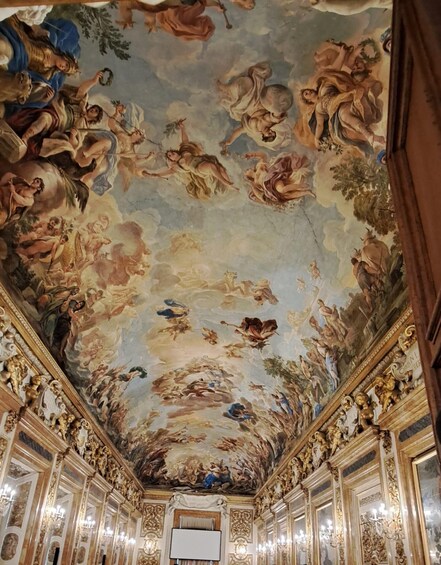 A grand hall with ornate ceiling frescoes and gilded architectural details. 1