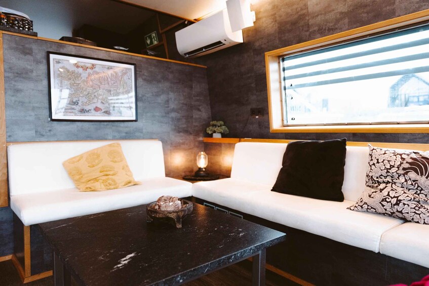 A modern living room with a white sofa, a black coffee table, and a window with blinds. 2
