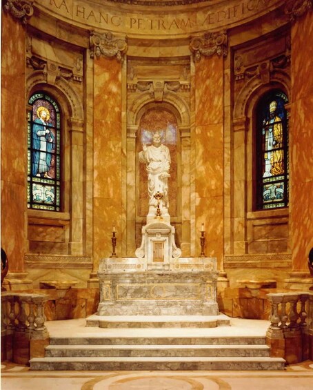A grand interior with a central statue, ornate columns, and stained glass windows. 2