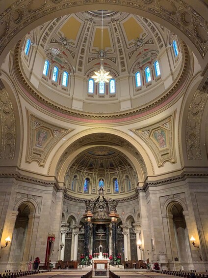 An ornate church interior with a high ceiling, stained glass windows, and a central altar. 4