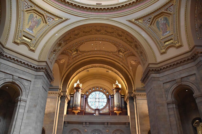 An ornate church interior with a large stained glass window, gold detailing, and statues. 5
