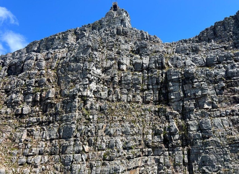 A rugged mountain peak with a small tower structure at the summit. 2