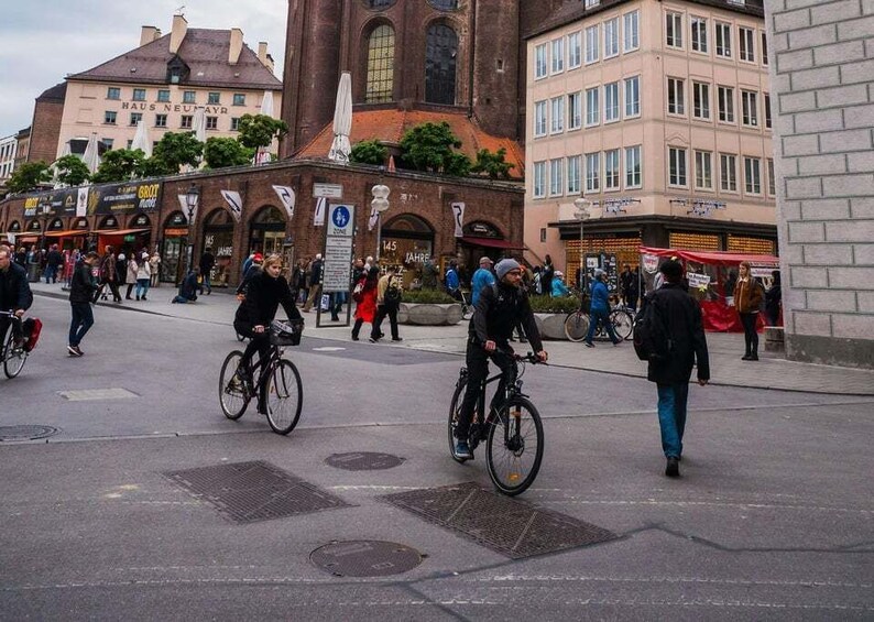 A busy urban square with cyclists, pedestrians, and historic buildings. 5