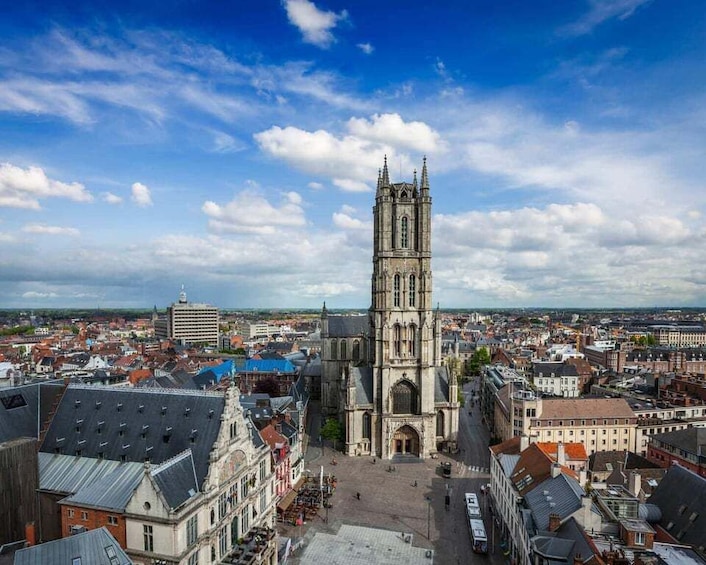 A historic cathedral with a tall tower, surrounded by a cityscape with various buildings and a clear sky. 1