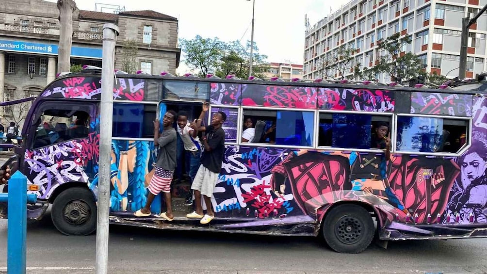 A graffiti-covered bus with passengers standing and interacting. 2