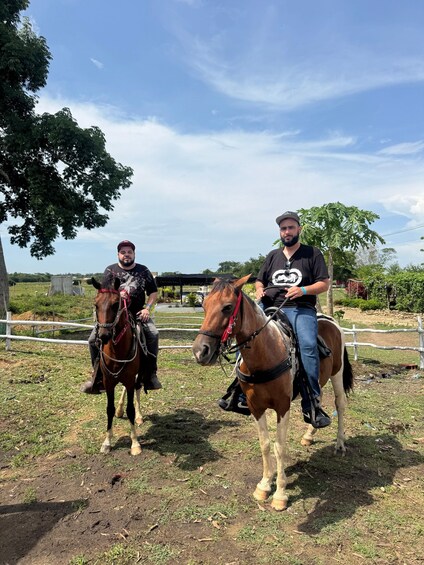 Two people riding horses in an outdoor setting with trees and a fence. 5