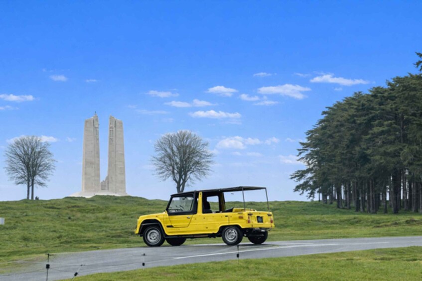 A yellow off-road vehicle on a road with a monument in the background. 3