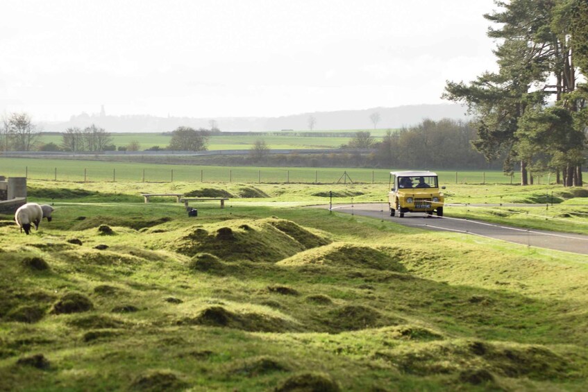 A rural landscape with a winding road, green fields, a sheep, and a yellow vehicle. 2