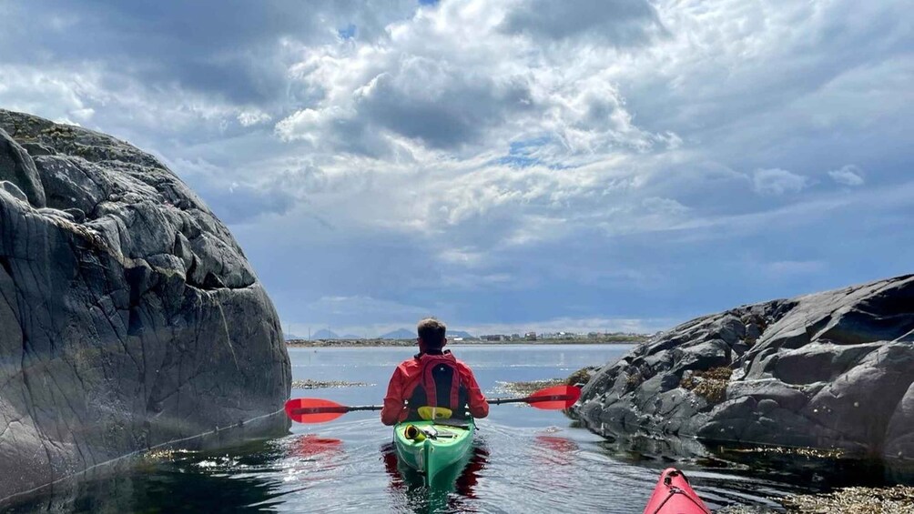 A person kayaking between large rocks in a body of water. 2