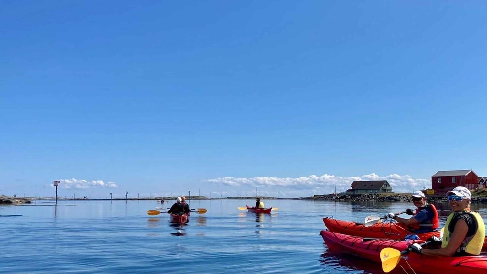 A calm body of water with kayaks and a red building in the background. 1