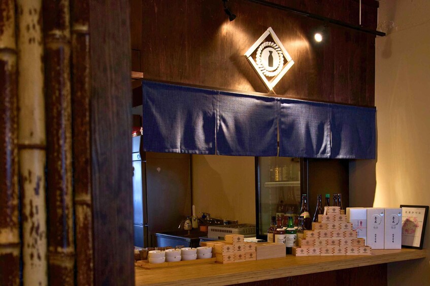 Un bar avec un auvent bleu, des étagères remplies de bouteilles et des cartons de marchandises. 5