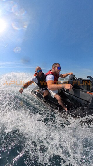 Two people on a jet ski, wearing life jackets, with water splashing around them. 4