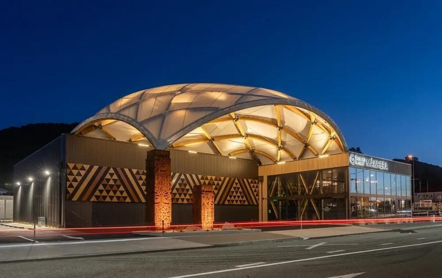 A modern building with a large, illuminated dome structure at dusk. 4