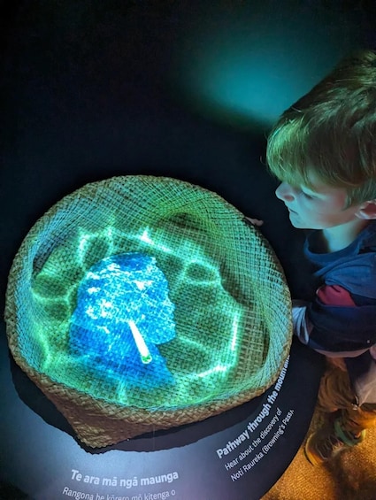 A child observing a glowing, circular display with text and a light blue object at the center. 2