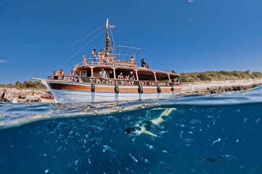 Un bateau appelé « Pirates Boat » transportant des passagers, naviguant près d’une plage. 4